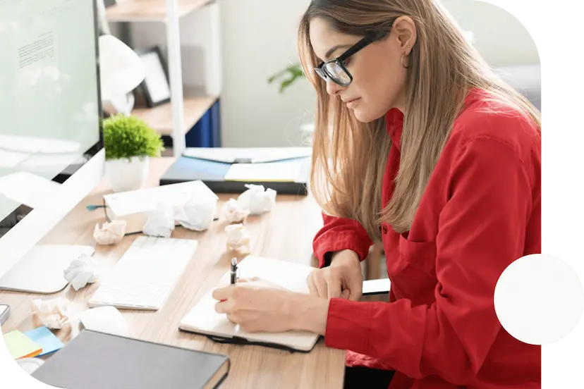 Woman-sitting-at-her-desk-writing-in-her-notebook