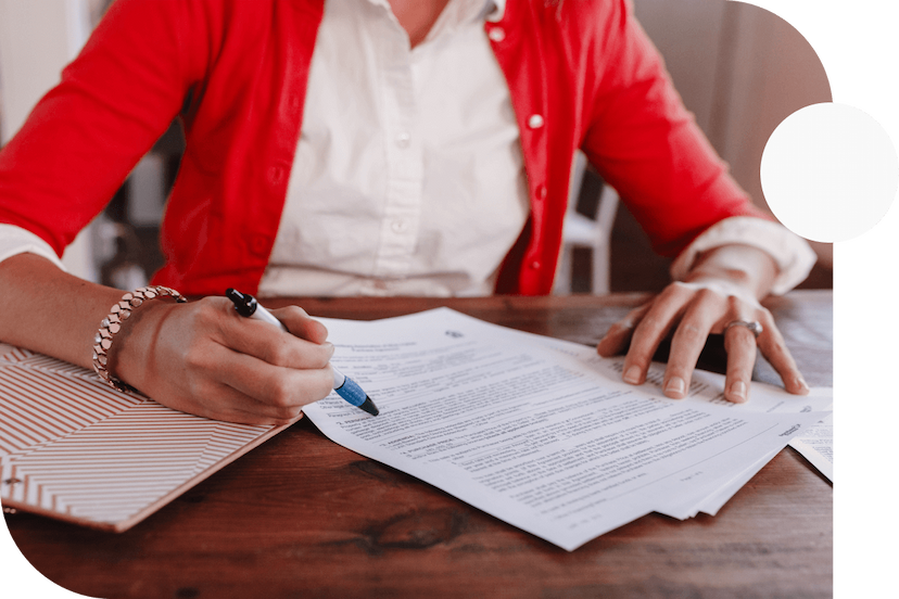 Person-in-red-shirt-holding-a-pen-in-their-right-hand-while-looking-over-insurance-contract-documents-1