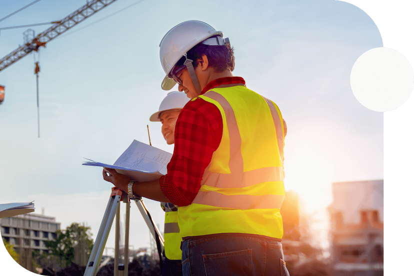 Two-construction-workers-in-reflective-vests-and-hard-hats-surveying-a-jobsite